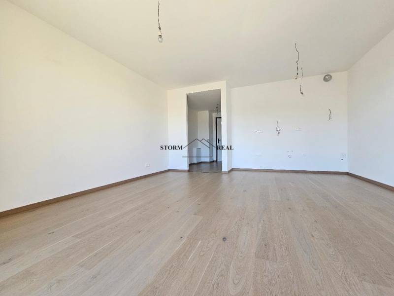 An empty room with a wood-patterned floor in a studio apartment.