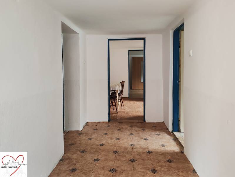 A hallway in a family house with tiles and furniture in the background.
