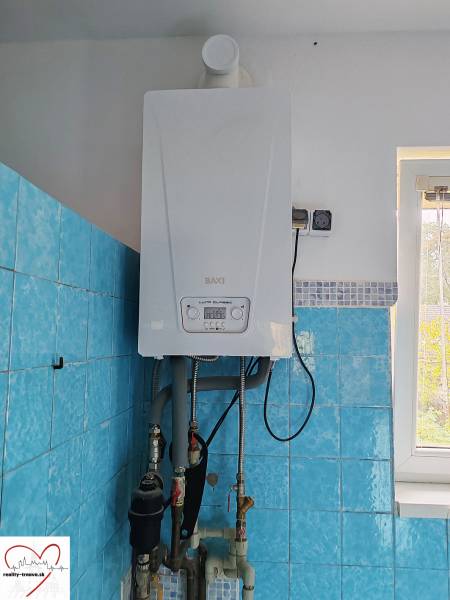 Gas boiler in a family house with blue tiles and a window.