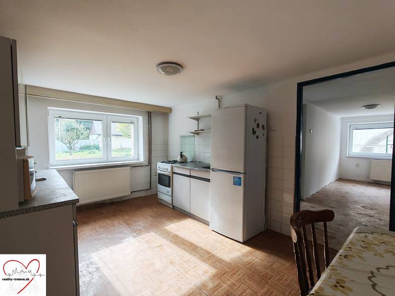 A kitchen in a family house with a wooden decor floor, equipped with appliances and a dining table.