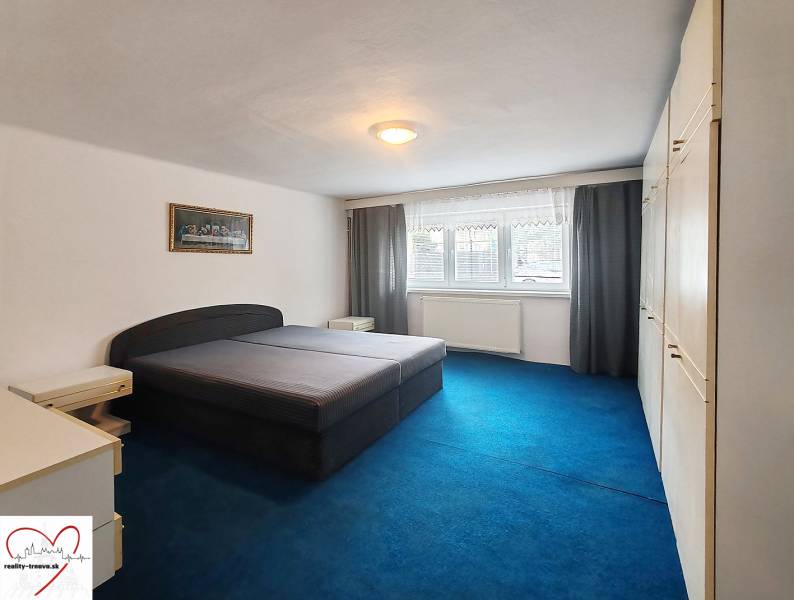 A bedroom in a family house with a large bed, a blue carpet, and a built-in wardrobe.