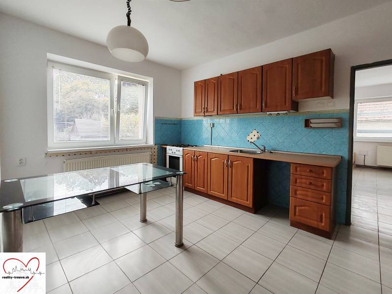 A kitchen in a family house with white tiles and wooden cabinets, glass table.