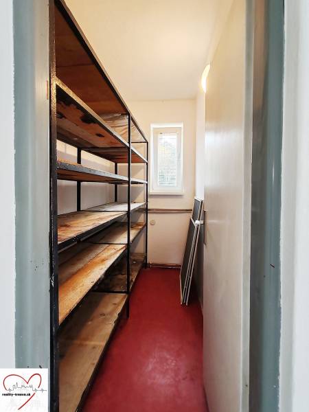 A narrow storage space in a family house with shelves and a red floor.
