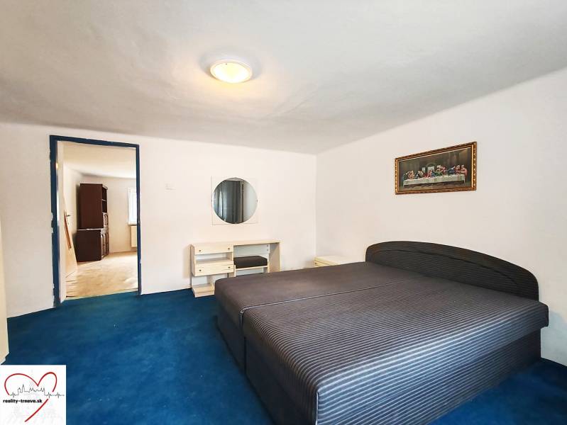 A bedroom in a family house with a large bed, a blue carpet, and a painting on the wall.