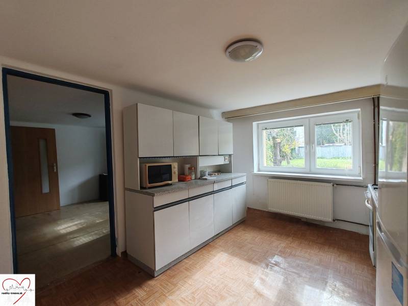 A kitchen in a family house with a wooden decor floor and a view of the garden.