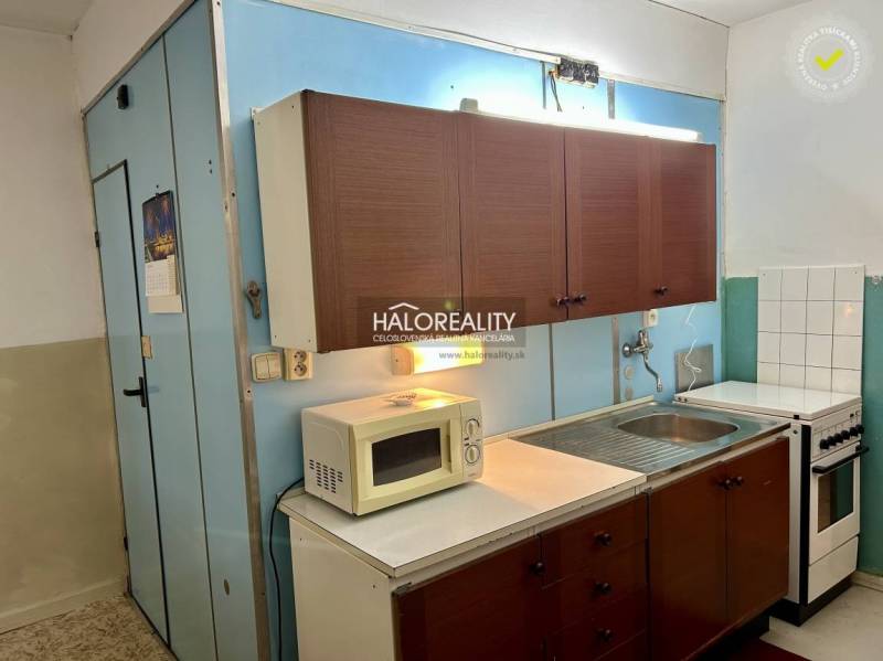 A kitchen with older cabinets, a microwave, and a stove in a 4-room apartment.