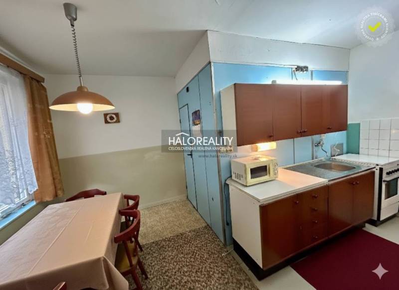 Dining room with a table and kitchen in a 4-room apartment, equipped with cabinets and appliances.