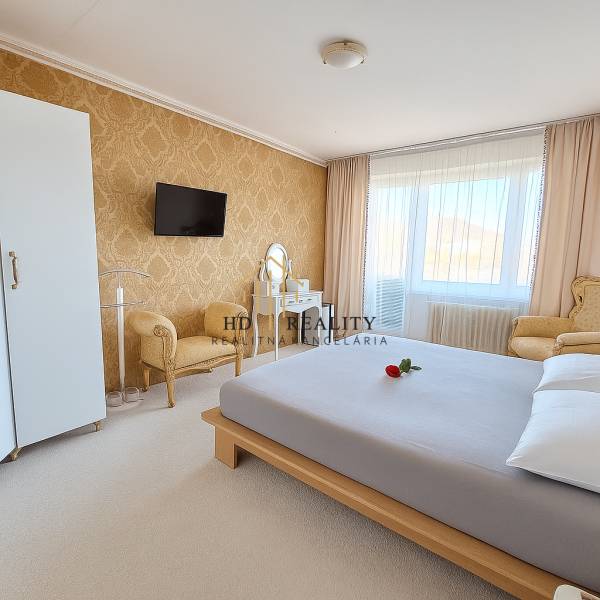 A bedroom in a 3-room apartment with elegant furniture, golden wallpaper, and a white carpet.