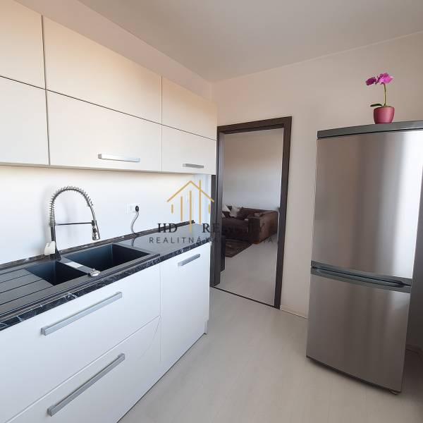 Kitchen in a 3-room apartment with a stainless steel refrigerator and a countertop, floor with wood decor.