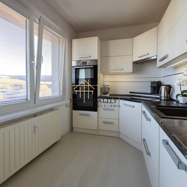 The kitchen in a 3-room apartment with a wooden decor floor, light kitchen cabinets.