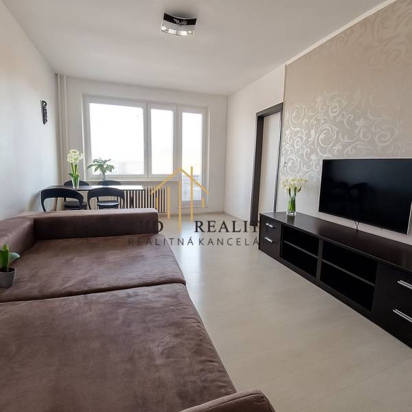 Living room in a 3-room apartment with a large sofa, TV, and flooring with a wooden decor.