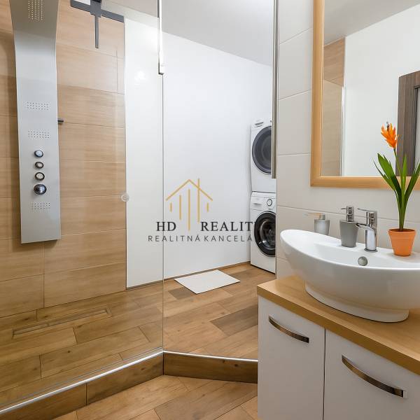 Bathroom in a 3-room apartment with a sink, shower, and washing machine, featuring a floor with a wooden decor.
