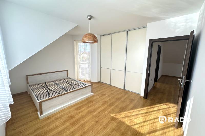 A bedroom in a family house with a bed, built-in wardrobe, and floor with wood decor.
