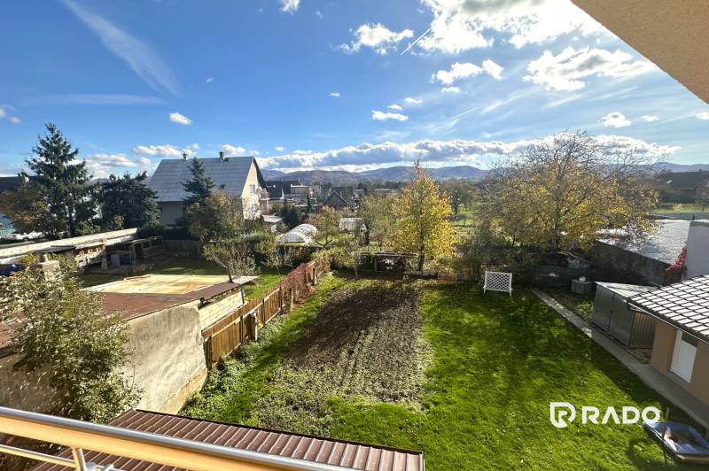 A garden at a family house in Bolešov with a view of the mountains, lawn, and trees.