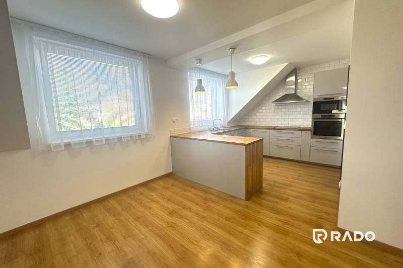 A kitchen in a family house with a wooden decor floor and light curtains on the windows.
