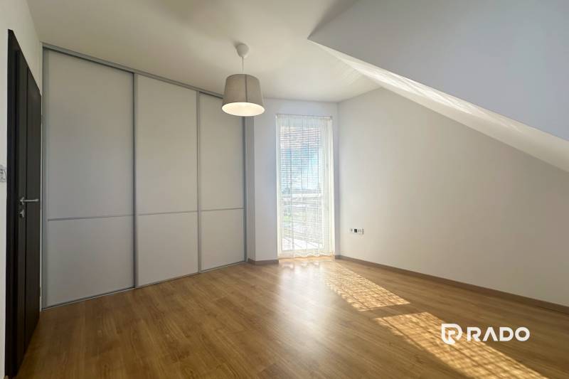 Interior of a building with wood-patterned flooring, a built-in wardrobe, and a window with a blind.