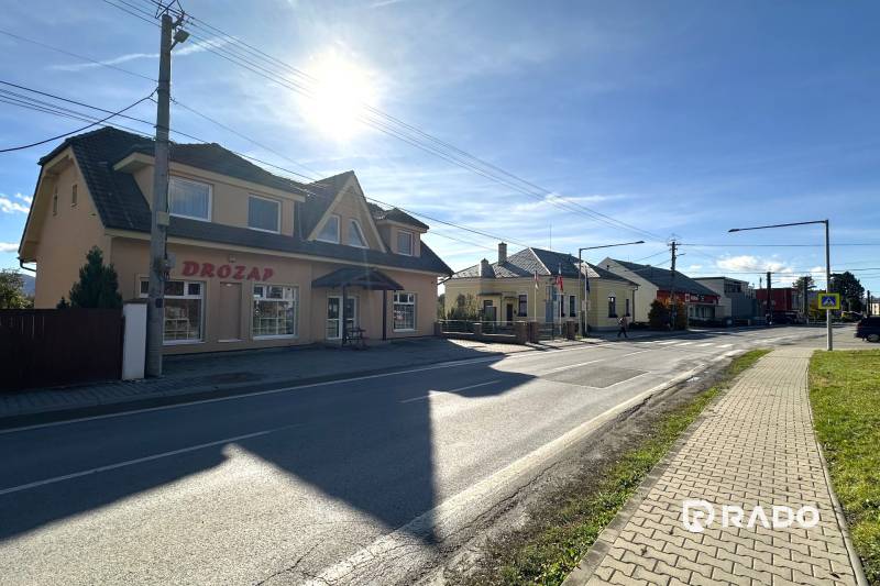 A street with shops in Bolešov, next to a family house, in daylight.