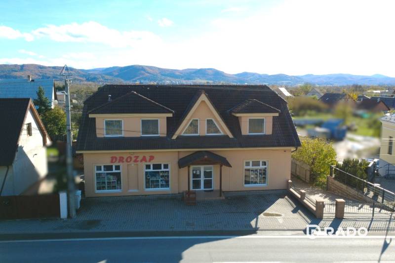 A family house in Bolešov with a shop on the ground floor and a mountain backdrop.
