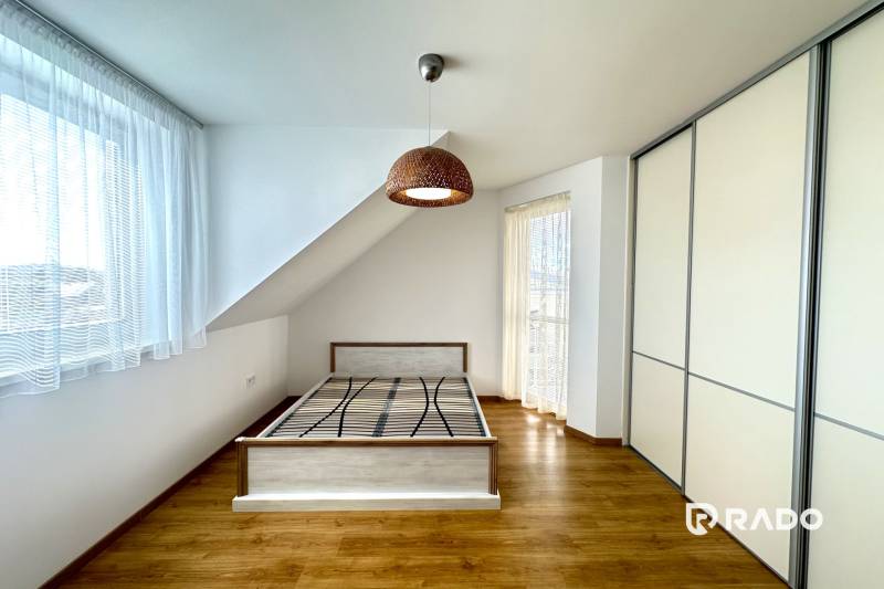 A bright room with a bed, built-in wardrobe, and wood-decorated floor in a family house.
