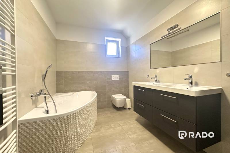 A bathroom with a bathtub, double sink, and mirror in a family house.