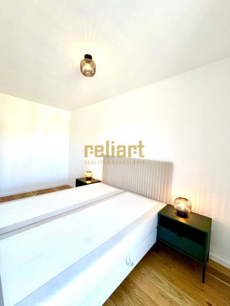 A bedroom in a two-room apartment with a wooden decor floor and nightstands.