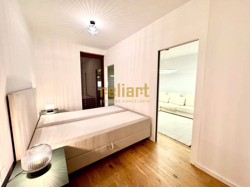 A bedroom with a bed, nightstands, and a wooden decor floor in a two-room apartment.