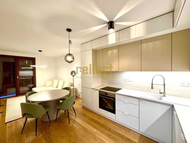 A kitchen in a 2-room apartment with a wooden decor floor and a dining table.
