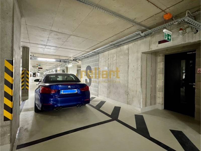 Underground parking lot with a blue car and escape signs.