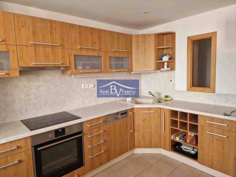 A kitchen in a 2-room apartment with wooden cabinets and a kitchen counter.