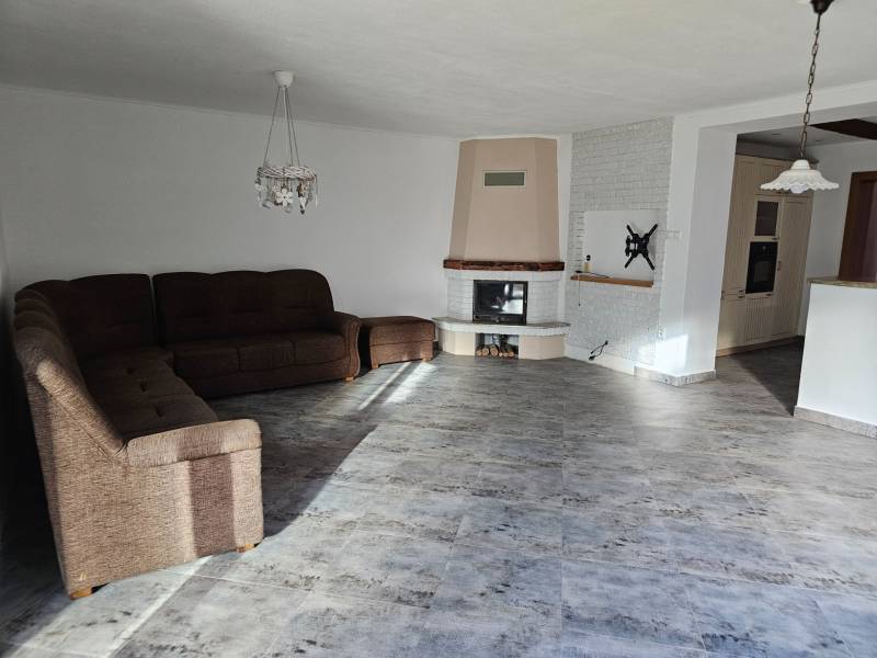 Living room in a family house with a wooden decor floor and a corner sofa.
