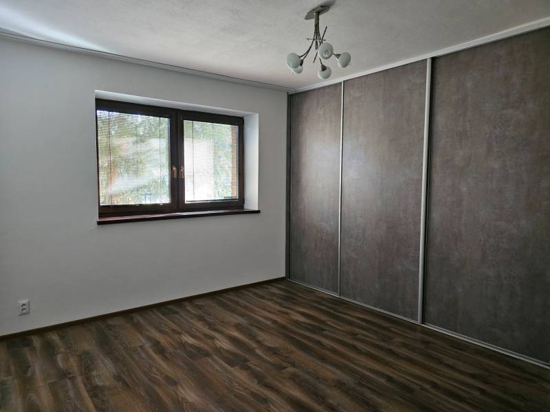 A room in a family house with a wooden decor floor and a large built-in wardrobe.
