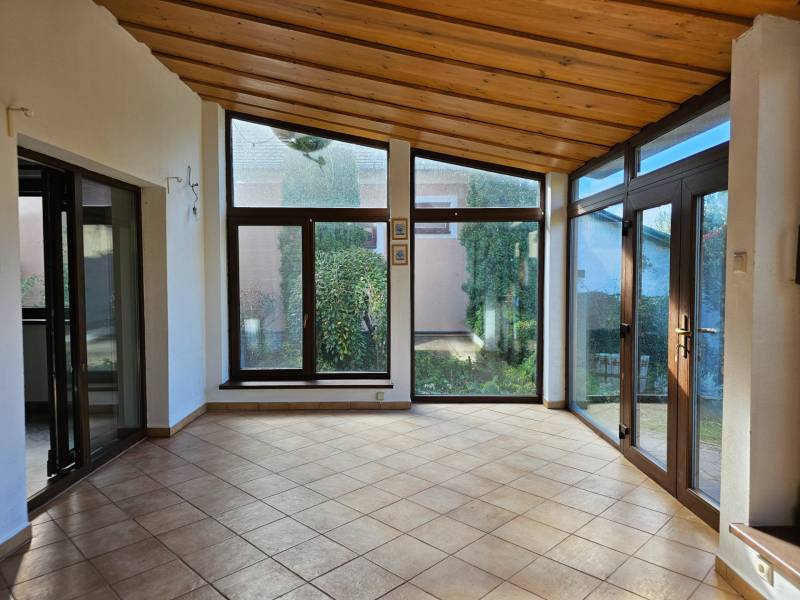A room in a family house with large windows and tiles, view of the garden.