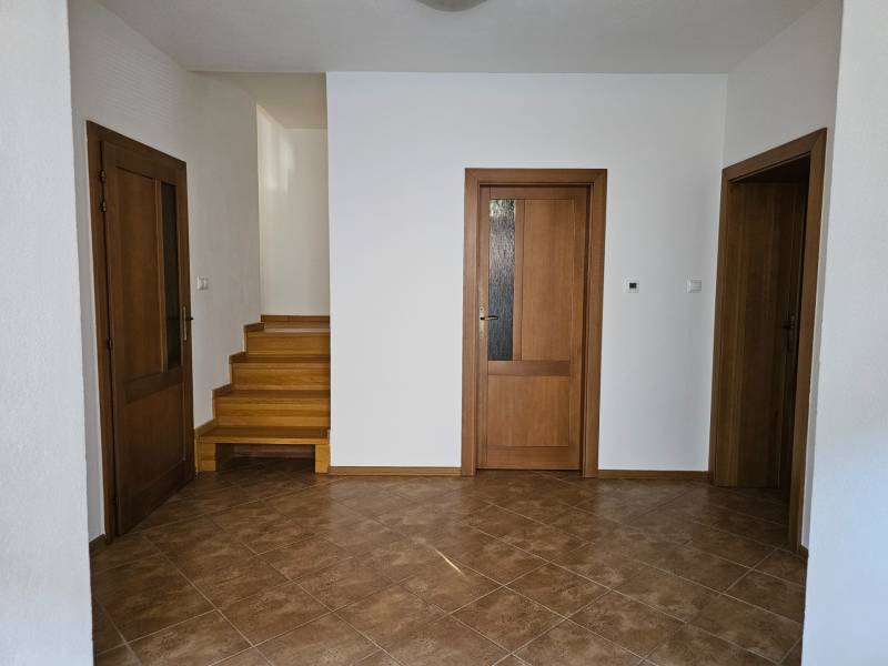 Interior of a family house with ceramic tiles, wooden stairs, and doors with glazing.