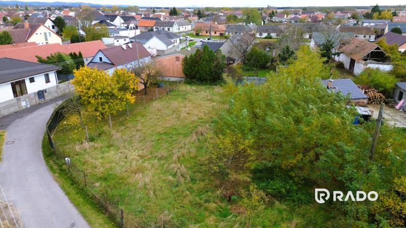 A plot of land in Gajary, designated for residential use, surrounded by neighboring houses.