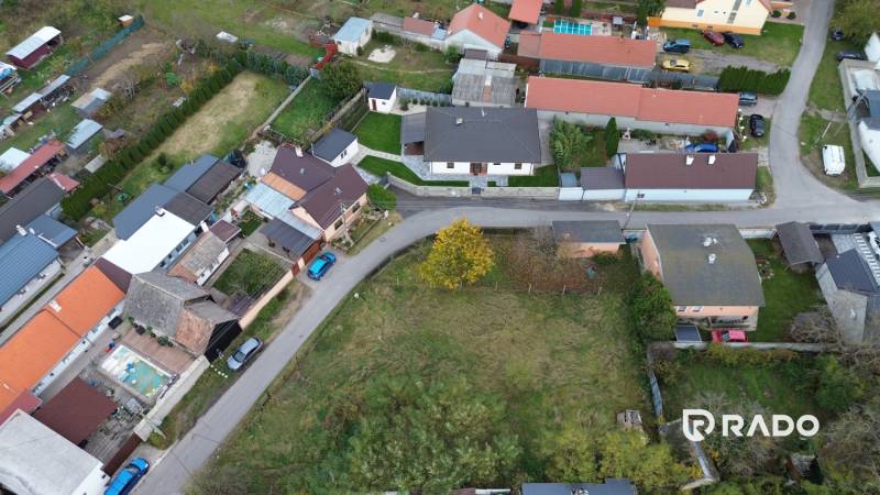 Aerial view of residential plots in Gajary with adjacent road and houses.