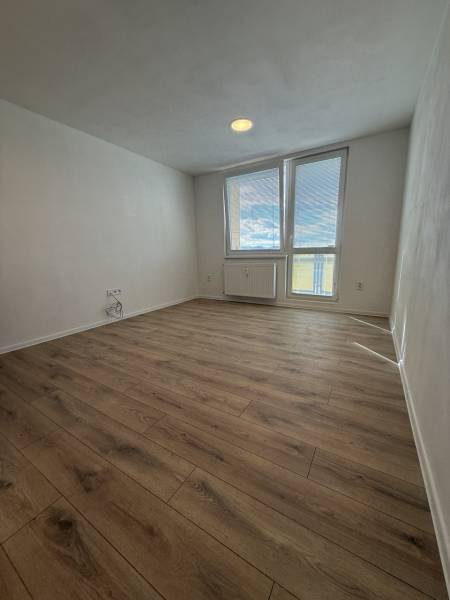 A room with a wooden floor decor, large window and radiator, studio apartment.
