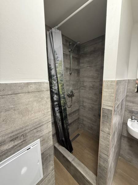 Shower corner with tiles and a curtain in a studio apartment. Floor with a wooden decor.