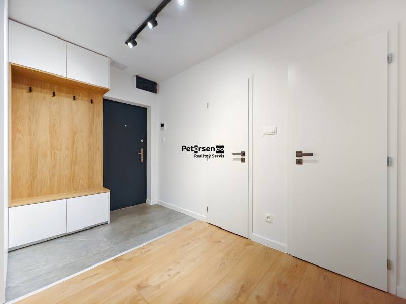Entrance hall of a two-room apartment with a wooden decor floor and storage space.
