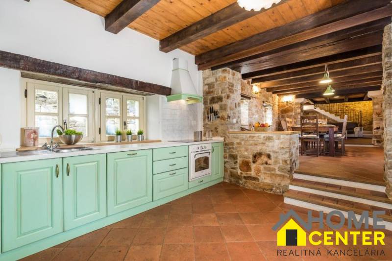 A rural kitchen of a villa with stone walls and a wooden decor floor.