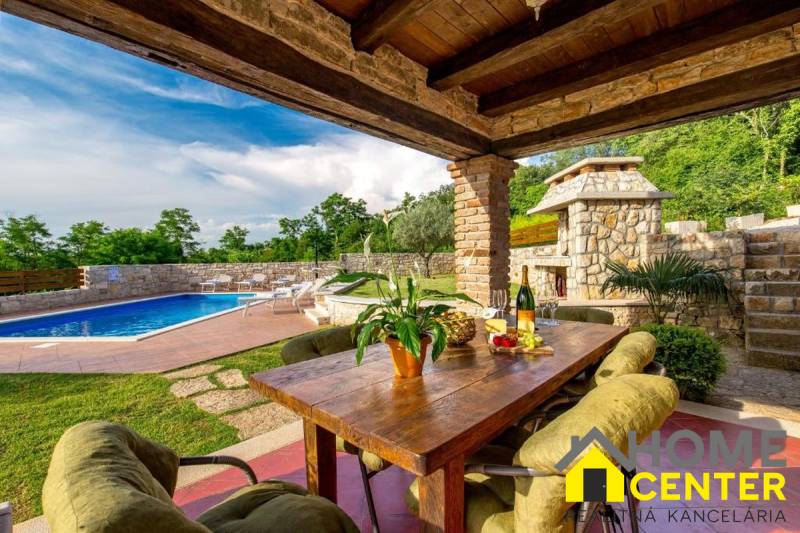 Exterior of a villa in the town of Bale with a pool, table, and natural details.