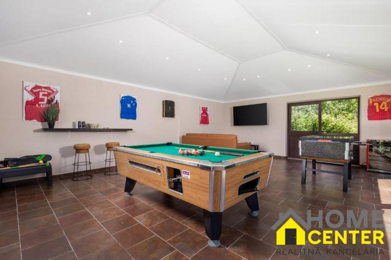 Interior of a villa with a billiard table, leather sofa, and wooden decor flooring.
