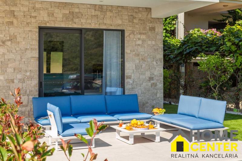 The exterior of the villa in Bale with blue garden seating and a stone wall.