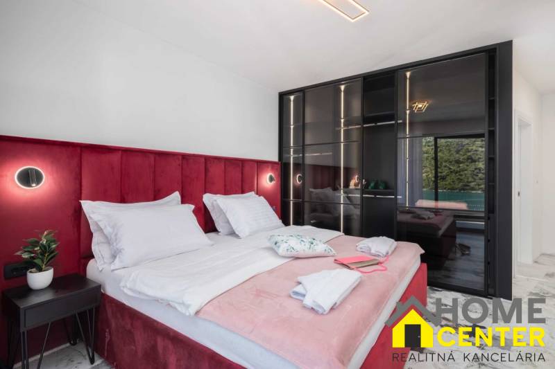 Bedroom in a villa with a bed upholstered in red velvet and a glass wardrobe.