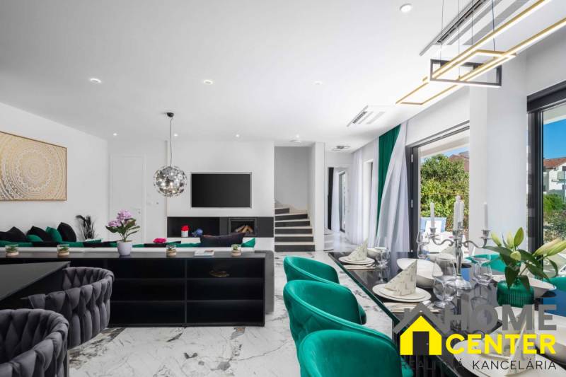 A bright living room in a villa with a marble floor, green armchairs, and modern accessories.