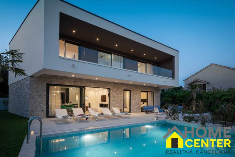 A villa in Bali with a pool, loungers, and a terrace at dusk.