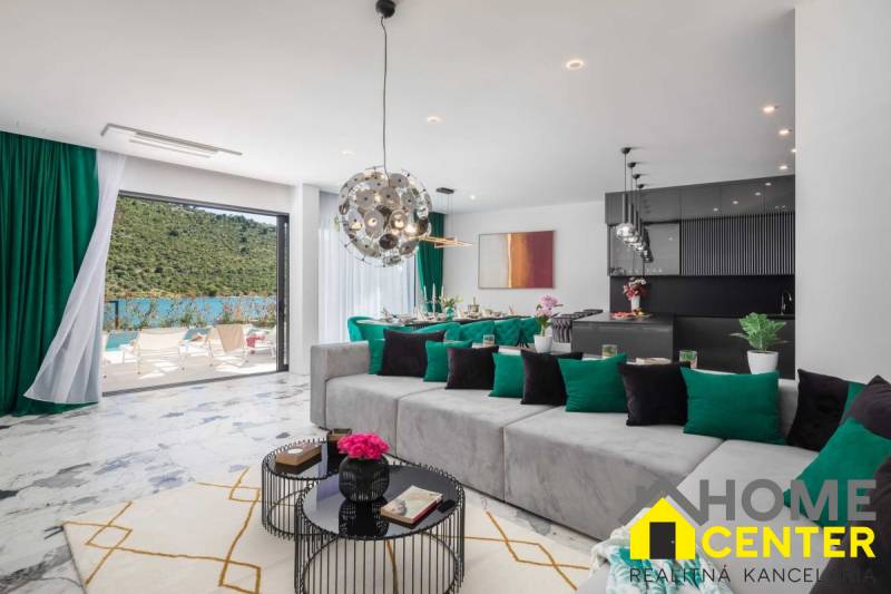 A spacious living room of the villa with a view of the pool and natural surroundings.