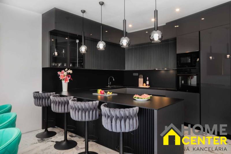 Black kitchen in a villa with marble flooring and luxurious chairs.