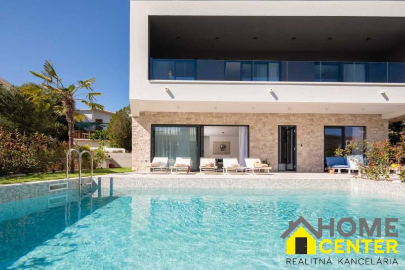 Villa in Bali with a pool, palm trees, terrace, and sunbeds in the background.