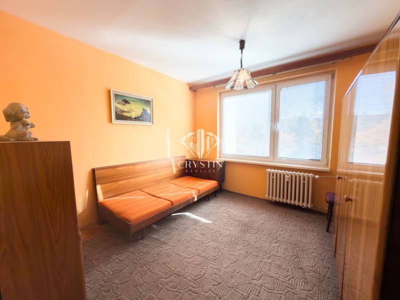 A room in a 3-room apartment with orange walls, a sofa, and a large window.