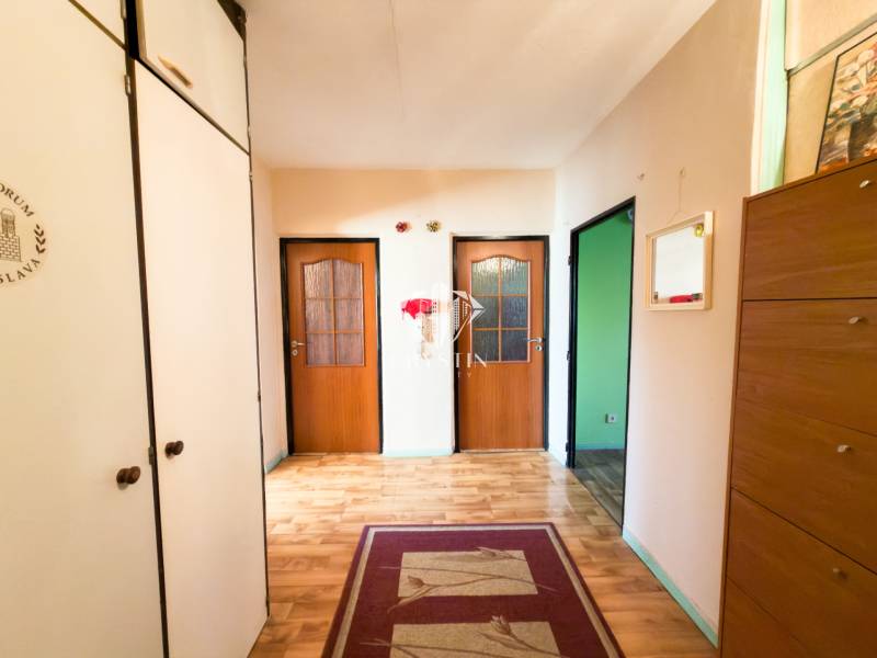 A hallway with closets, light walls, a floor with wood decor, a 3-room apartment.